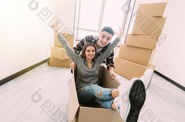 在搬家日，这对幸福的夫妇正在新居里玩纸板箱。