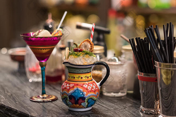 酒吧柜台上摆着红案的酒杯和原汁原味的彩绘坛子，里面放着鸡尾酒工具和配料。