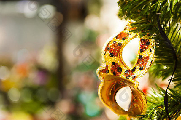 美丽的狂欢节面具挂在圣诞树上，背景是明亮的圣诞装饰