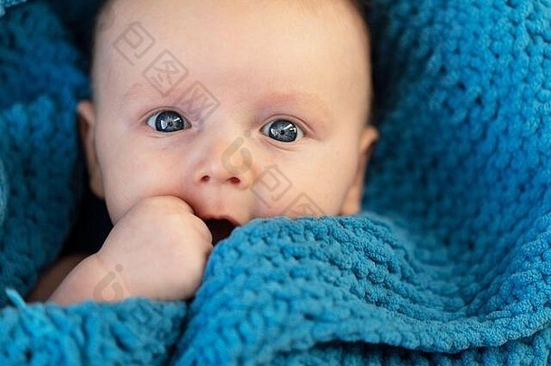 一个可爱的小男孩抱着一条柔软的蓝色毯子