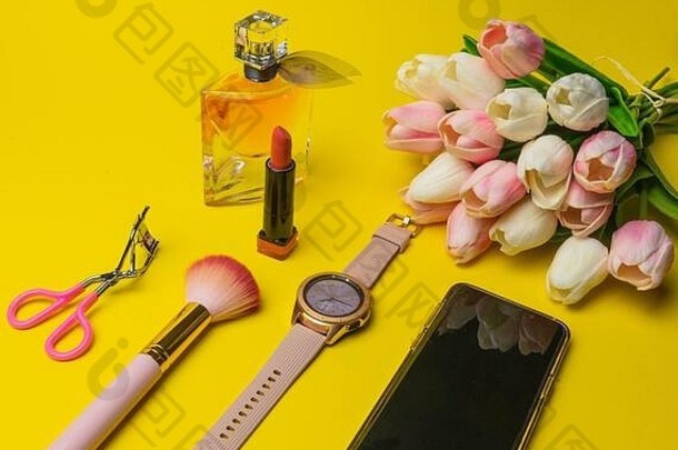 化妆产品方丹、睫毛膏、香水、刷子、花卉钟、手机及黄色背景的<strong>化妆包</strong>