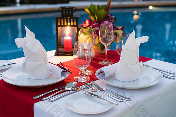 浪漫的烛光餐桌；池边有桌子。