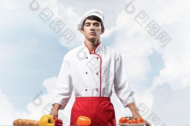 年轻的男厨师站在餐桌旁