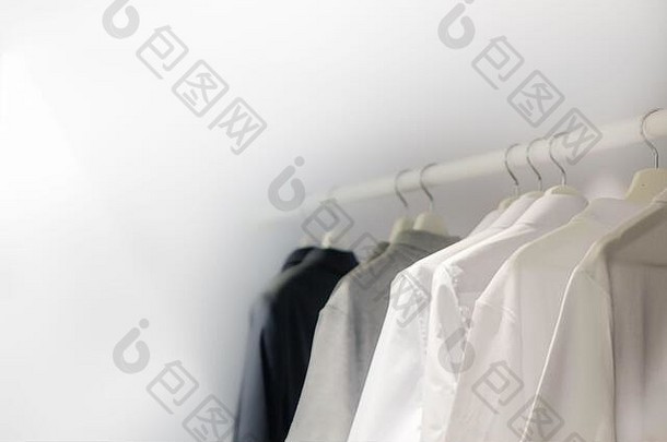 白色t恤挂在梳妆台上，黑色、灰色布料挂在衣柜上，干净的洗衣房白色背景空间