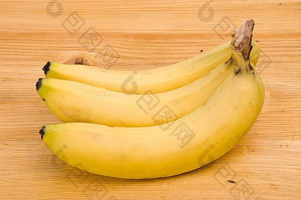 三个新鲜的黄色香蕉被隔离在木桌上