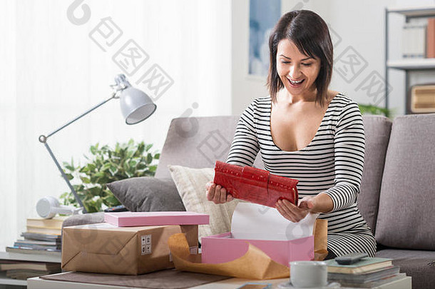 快乐女人拆开一个包裹，里面装着一个时尚包，网上购物，送货和顾客满意的理念
