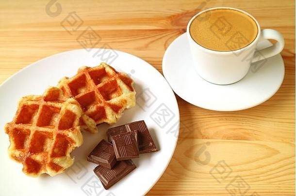 一盘比利时华夫饼和黑巧克力方块，背景是浓缩咖啡