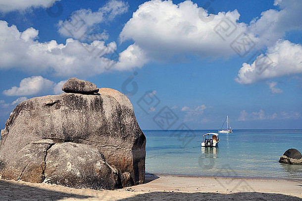 背景是岩石和船只的海滩