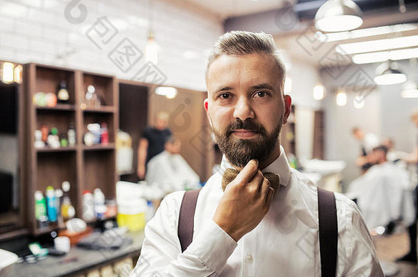 一张英俊的时髦男人客户站在理发店的肖像。
