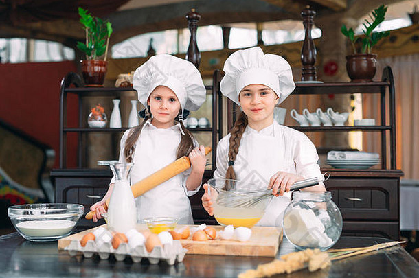 有趣的女孩孩子们正在厨房里准备面团。