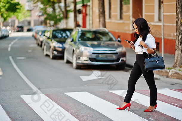时尚的非裔美国女商人在城市街道上的人行横道上。