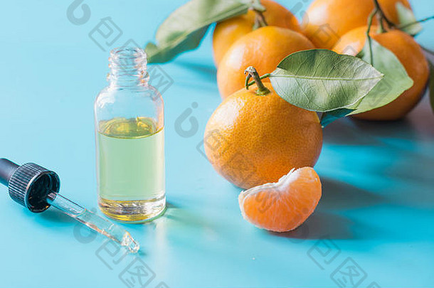 橙色柑桔精油装在玻璃瓶中，淡蓝色背景。护肤概念。