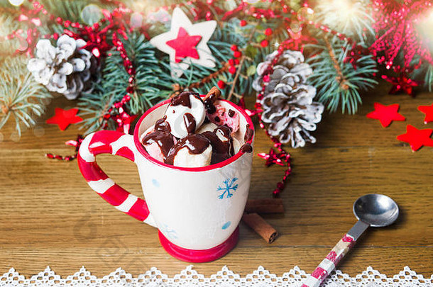五颜六色的棉花糖和巧克力放在一个带有节日装饰的杯子里