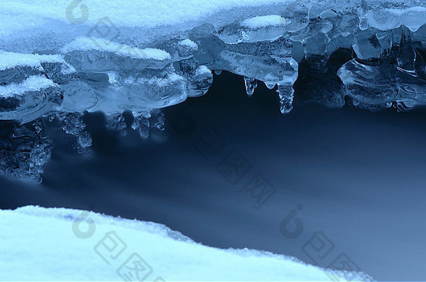 冬季河流冰洞和美丽的冰冻冰形状和水流蓝色冬日宏观照片