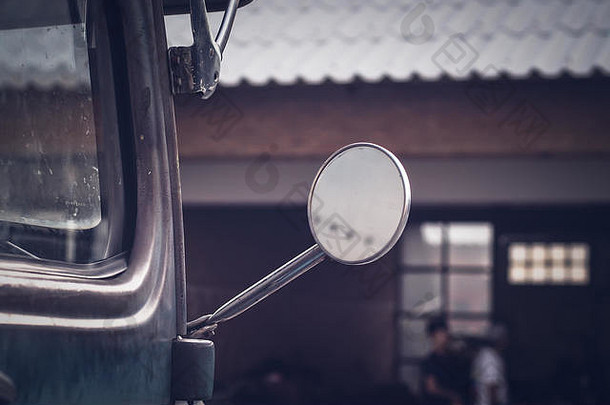 一辆老式汽车上驾驶镜的特写镜头。旧仓库模糊背景