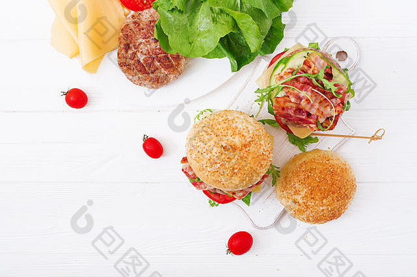 大三明治-汉堡包汉堡配牛肉、奶酪、西红柿、黄瓜和炸培根。平铺。俯视图