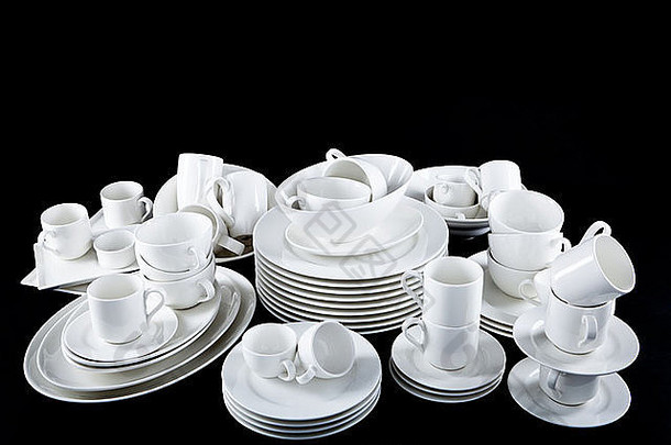 黑色背景上隔离的一堆混合的白色盘子、杯子和盘子