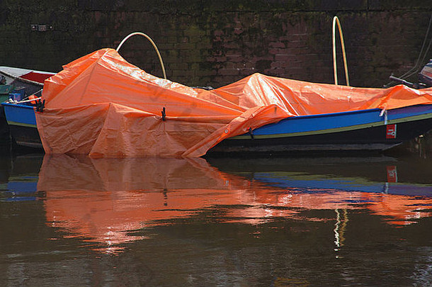 2006年4月24日，荷兰阿姆斯特丹运河的水面上，一艘蓝色的船上覆盖着一层橙色的塑料防水布