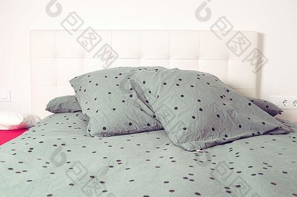 室内卧室<strong>家居场景</strong>中带有黑点的绿色枕头和床单