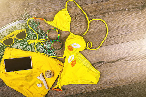 集海滩衣服黄色的比基尼手镯短裤眼镜黑暗木背景前视图夏天假期概念