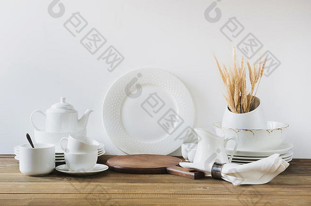 白色厨房用具、餐具和其他不同的白色材料，用于白色木板上。空间。