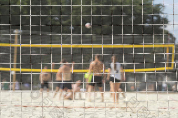 夏日，一群年轻朋友在沙滩上打排球，选择聚焦。模糊的背景，健康的生活方式
