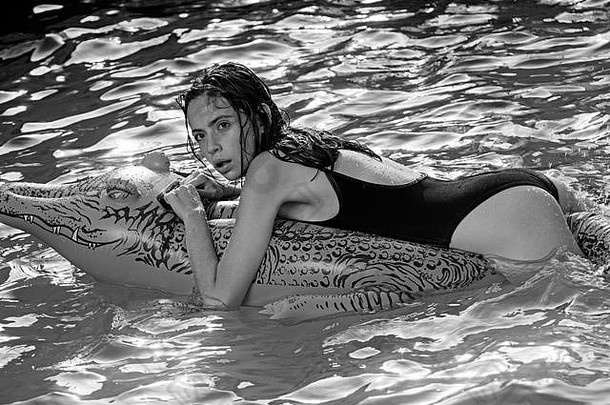 时尚鳄鱼皮和水中女孩。带着充气床垫在海上的女人。在豪华游泳池放松。《鳄鱼上的女孩历险记》