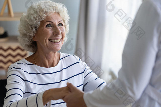 快乐的奶奶患者牵着护理者的援助之手站了起来