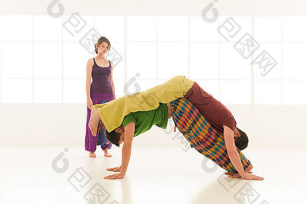 三个年轻人一个女人和两个男人在后台窗口的课堂上练习瑜伽