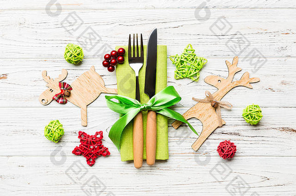 餐巾纸上新年用具的俯视图，带有节日装饰和木制背景上的驯鹿。圣诞晚餐概念的特写镜头。