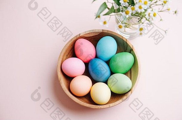 复活节图片，木制盘子里的彩色彩蛋，粉红色背景