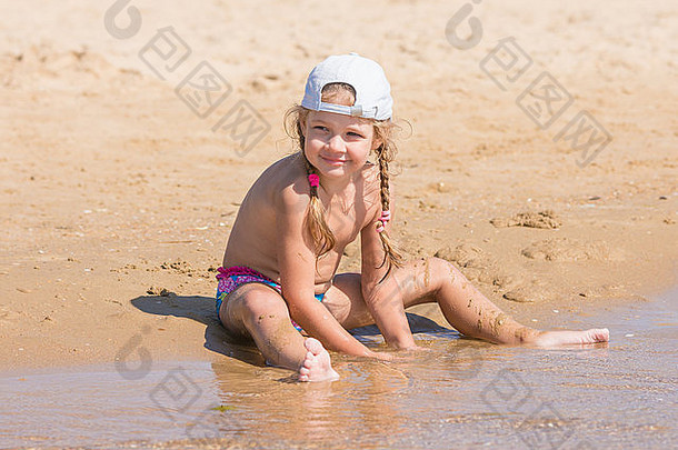 戴帽子的五岁女孩坐在沙滩上