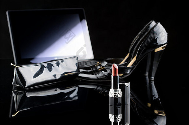 笔记本电脑、口红和鞋子。黑色<strong>背景</strong>。女套装。网上购买化妆品