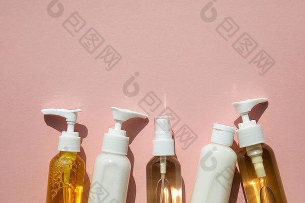 粉红色背景的透明瓶装美容化妆品产品系列
