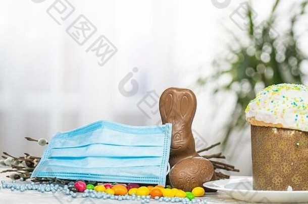 复活节蛋糕，医用防护面罩，巧克力蛋和兔子，特写。对病毒的保护。庆祝圣日的概念