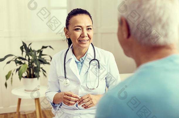 开朗的医生微笑着与老年患者交谈