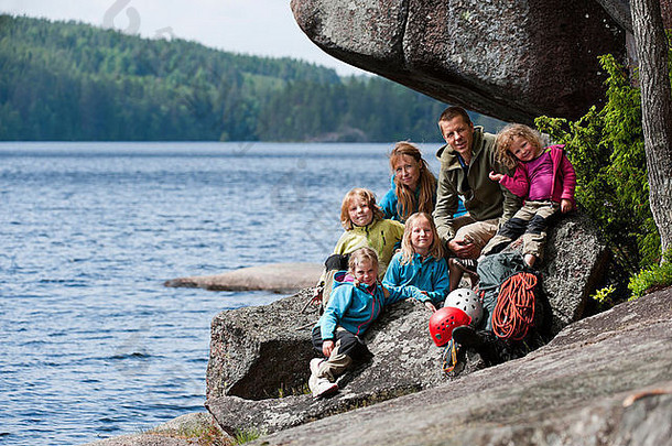 一家人带着四个孩子带着攀岩设备坐在岩石附近