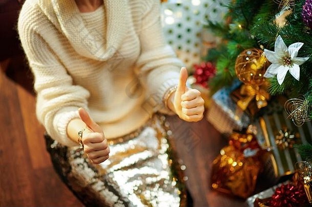 特写镜头现代家庭主妇黄金金片裙子白色毛衣装饰圣诞节树现在盒子显示拇指