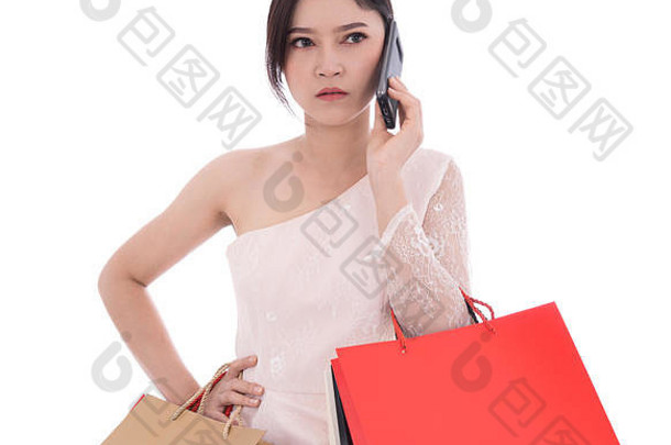 一个不开心的女人在智能手机上聊天，手上拿着购物袋，背景是白色的