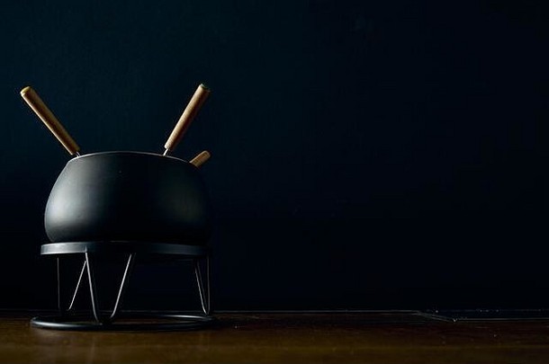 厨房场景用于烹饪<strong>火锅</strong>的黑色平底锅位于黑色背景的木桌上