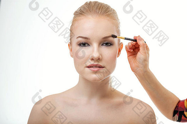 化妆师正在制作模特眉毛。正在化妆的年轻女子美丽脸庞的特写镜头。