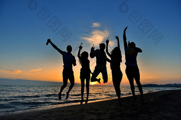 一群快乐的年轻人在美丽的夏日夕阳下在海滩上跳舞