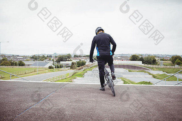 骑自行车的人站在起跑坡道上，带着BMX自行车