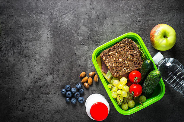 午餐盒里有三明治、水果、蔬菜、水。