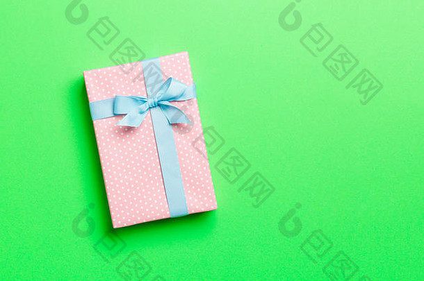 用绿色背景上的蓝丝带用纸包装圣诞或其他节日手工礼品。礼品盒，彩台礼品装饰，t
