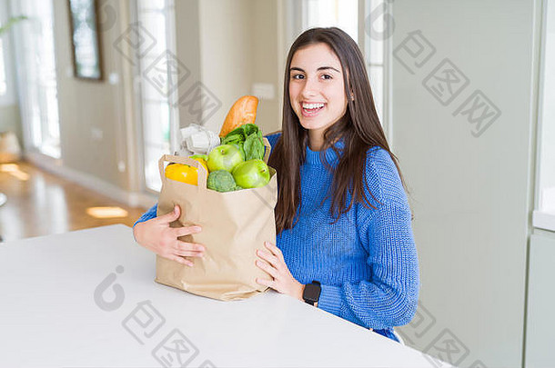 年轻的美丽的女人微笑持有纸袋完整的食品杂货首页