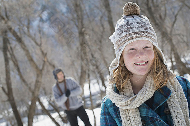 冬天的景色地上有雪一个戴着纱<strong>帽</strong>和围巾的小女孩在户外一个男人在后面