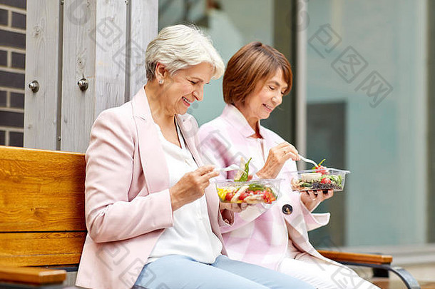 在城市街道上<strong>吃外卖</strong>食物的老年妇女