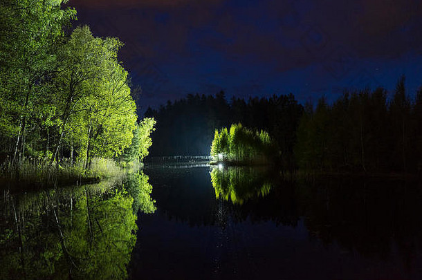 在漆黑的夜晚站在户外用手电筒照明的男人。瑞典自然和风景的神秘和抽象照片。