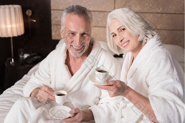 幸福快乐的老年夫妇在床上喝咖啡